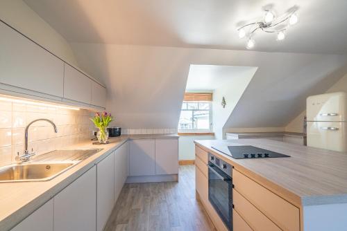 a kitchen with white cabinets and a sink at Morvern in Tobermory