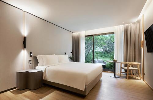 a bedroom with a bed and a large window at dusitD2 Hua Hin in Hua Hin