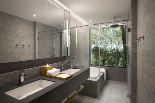 uma casa de banho com um lavatório, uma banheira e um espelho. em dusitD2 Hua Hin em Hua Hin
