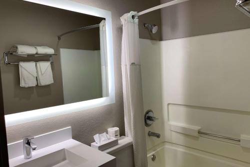 a bathroom with a sink and a mirror and a tub at Super 8 by Wyndham Greeley in Greeley