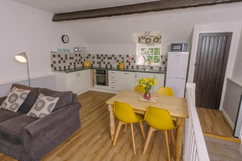 a kitchen and living room with a table and yellow chairs at Corffe House and Holiday Cottages in Barnstaple