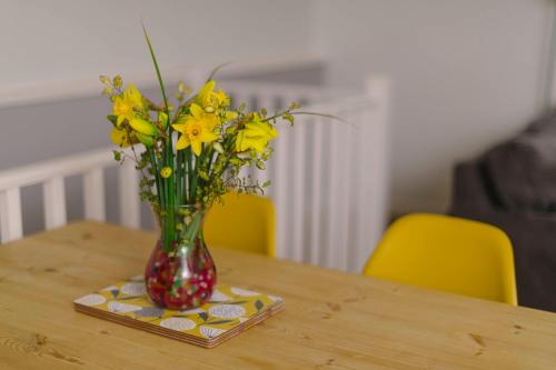 a vase with yellow flowers sitting on a table at Corffe House and Holiday Cottages in Barnstaple