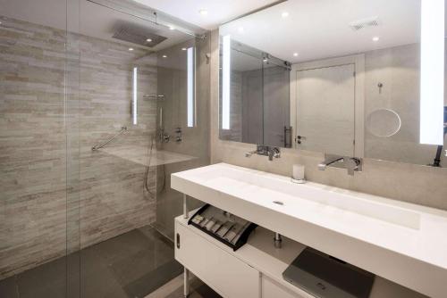 La salle de bains est pourvue d'un lavabo blanc et d'une douche. dans l'établissement Port de Plaisance Resort, Trademark Collection by Wyndham, à Philipsburg