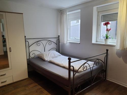a bed in a room with two windows at Westerwald Apartments in Straßenhaus