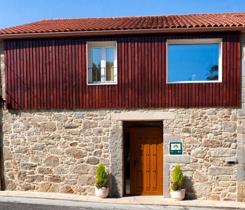 a stone building with a wooden door and two potted plants at A Casa do Folgo Turismo Rural in Negreira