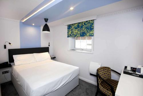 a bedroom with a bed and a chair and a window at St James Hotel; BW Premier Collection in Nottingham