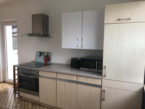 a kitchen with white cabinets and a stove and microwave at Ferienwohnung Im Bachgrund in Schlitz