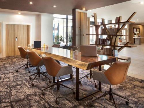 una sala da pranzo con un grande tavolo e sedie in legno di Novotel Lausanne Bussigny a Losanna