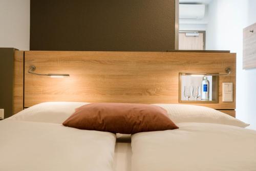 a bed with a wooden headboard with a pillow on it at Best Western Plus Kurhotel an der Obermaintherme in Bad Staffelstein