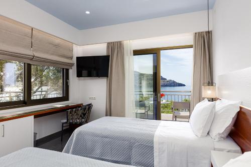 a hotel room with a bed and a desk and windows at CHRISTOS Élite Sea View Suite Adults Only in Plakias