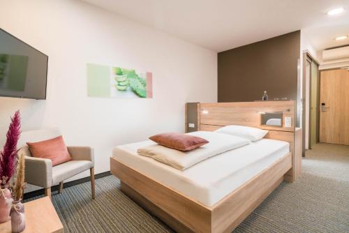 a bedroom with a large bed and a chair at Best Western Plus Kurhotel an der Obermaintherme in Bad Staffelstein