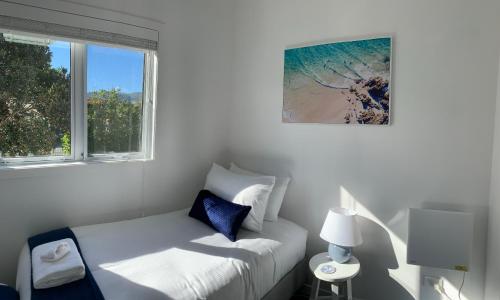 a white room with a bed and a window at Coromandel Town Harbourside Cottage Luxury Accommodation in Coromandel Town
