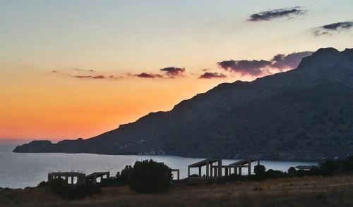 a sunset over a body of water with a mountain at Orionas in Tsoútsouros