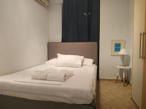 a bedroom with a bed with white sheets and pillows at Beautiful house by the sea,Loutraki Skaloma. in Loutraki