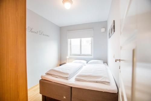 a bedroom with a bed with white sheets and a window at Frogner House - Lagårdsveien 13 in Stavanger