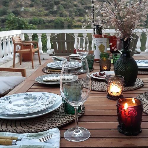 a wooden table with plates and wine glasses on it at Casa dos Vinhais Douro Valley in Coleja