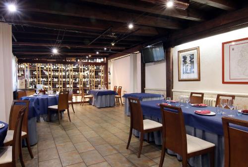 un comedor con mesas y sillas azules y estanterías de botellas de vino en HOTEL RURAL LOS ABUELOS, en Montemayor de Pililla