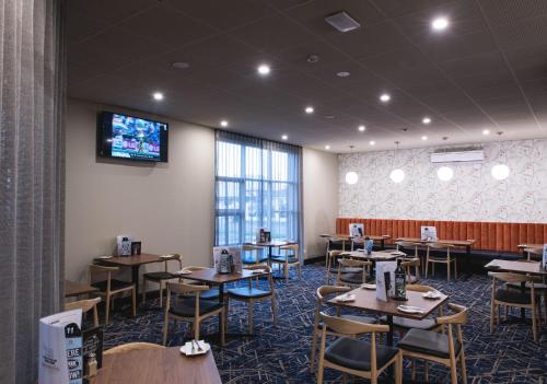 a dining room with tables and a tv on the wall at Nightcap at Hendon Hotel in Adelaide