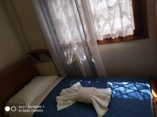 a bed with a towel on it in front of a window at Menelaos Apartments in Lefokastro