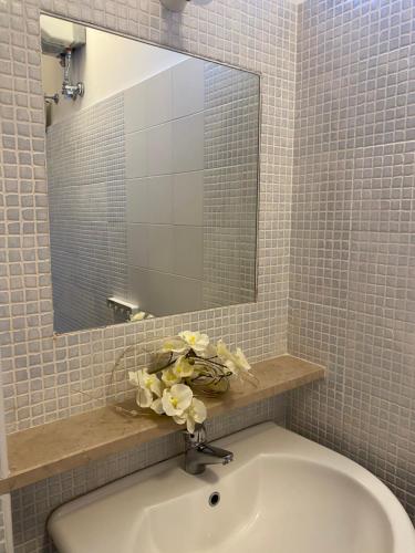 a bathroom with a sink with a mirror and flowers at B&B Vista Mare in Rodi Garganico