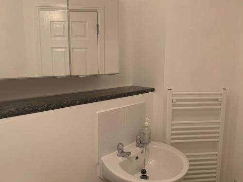a white bathroom with a sink and a mirror at Ayr Cozy Corner Apartment in Ayr