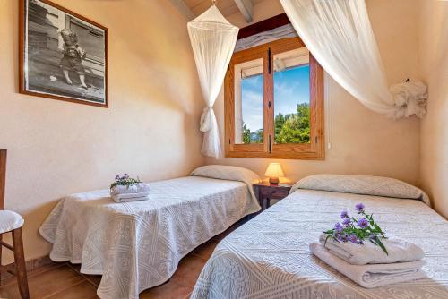 two beds in a room with a window at Country house with amazing pool in a beautiful rural setting in Campanet