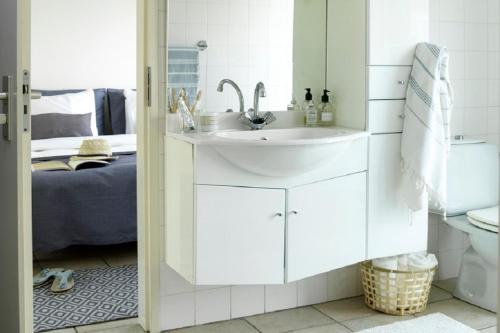 a white bathroom with a sink and a bed at Penthouse in Loosdrecht