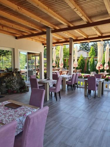 un restaurante con sillas moradas, mesas y ventanas en Guest House Mines, en Vrdnik