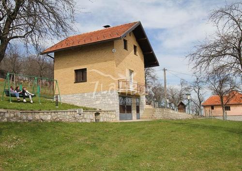 two people sitting on a swing in front of a building at VILA ANTONIJE in Šljivovica