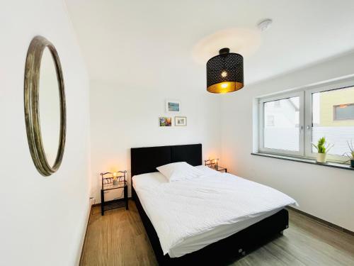 a white bedroom with a bed and a mirror at Ferienwohnung Mittelrhein Familie Lehmann in Niederburg