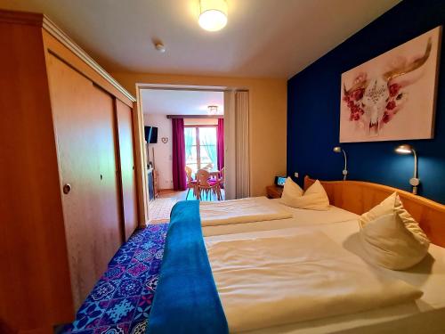 a hotel room with two beds and a blue wall at Appartementhaus „die Kuh am See“ (vormals Haus St. Leonhard) in Schliersee