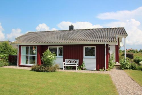 a red cottage with a bench in a yard at Tohuus in Wesselburenerkoog