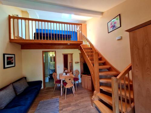 a living room with a wooden staircase and a dining room at Appartementhaus „die Kuh am See“ (vormals Haus St. Leonhard) in Schliersee