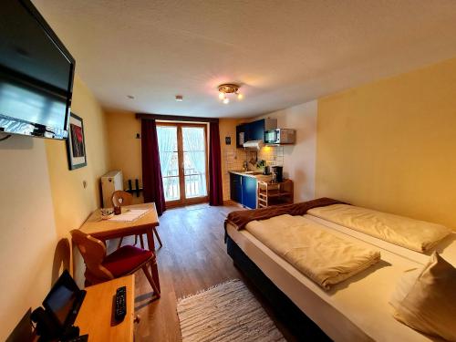 a bedroom with a bed and a television in it at Appartementhaus „die Kuh am See“ (vormals Haus St. Leonhard) in Schliersee