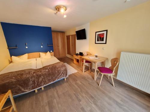 a hotel room with a bed and a table and a tv at Appartementhaus „die Kuh am See“ (vormals Haus St. Leonhard) in Schliersee