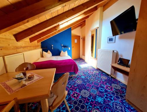 a bedroom with a bed and a table and a television at Appartementhaus „die Kuh am See“ (vormals Haus St. Leonhard) in Schliersee