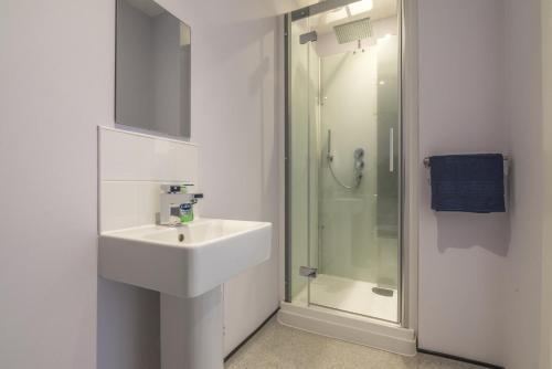 uma casa de banho branca com um lavatório e um chuveiro em No 4 Ocean Cabins - Saundersfoot Harbour - Saundersfoot em Saundersfoot