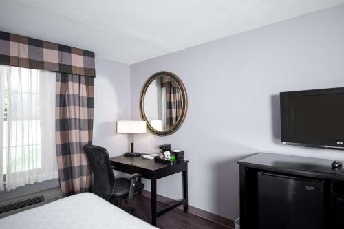 a hotel room with a desk and a television at Clarion Hotel & Conference Center Leesburg in Leesburg