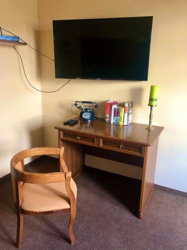 a desk with a chair and a television on a wall at KARÁM Vendégház és Lakásétterem in Nagybajcs