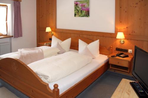 a bedroom with a bed with white sheets and a television at Ferienparadies Spielmannsau in Oberstdorf