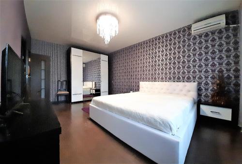 ヴォロネジにあるMEGAPOLIS улица Арсенальная 4-А-136の白いベッドと壁が備わるベッドルーム1室が備わります。