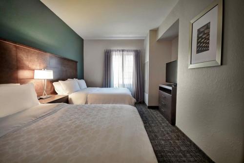 a hotel room with two beds and a television at Staybridge Suites - Southgate - Detroit Area by IHG in Southgate