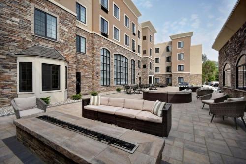 a patio with a couch and chairs in front of a building at Staybridge Suites - Southgate - Detroit Area by IHG in Southgate