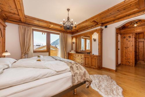 a bedroom with a large bed and a chandelier at Chalet Mountain Plaza - Apt Overland in Pinzolo