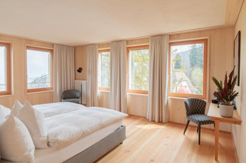 a bedroom with a bed and a desk and windows at Hotel Gasthaus Hergiswald in Eigenthal