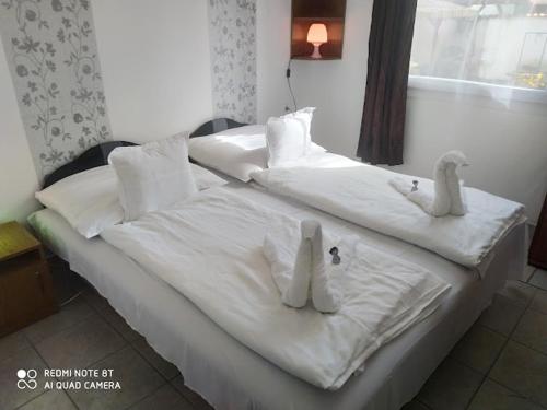 ハイドゥソボスローにあるMarabella Apartmanokの白いシーツとぬいぐるみが敷かれたベッド
