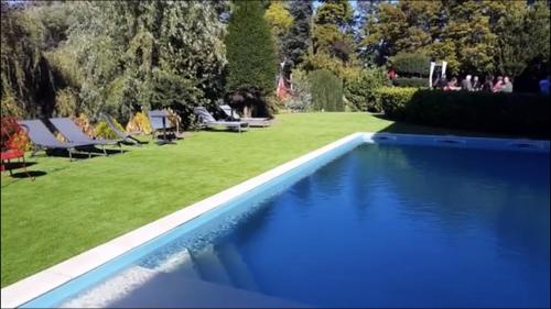 una piscina blu con sedie a sdraio e un prato di LE DOMAINE DE GORNETON a Chasse-sur-Rhône