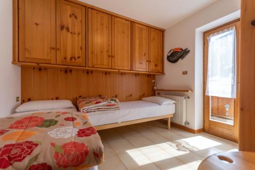 1 dormitorio con 1 cama y armarios de madera en Casa Parente en Pozza di Fassa