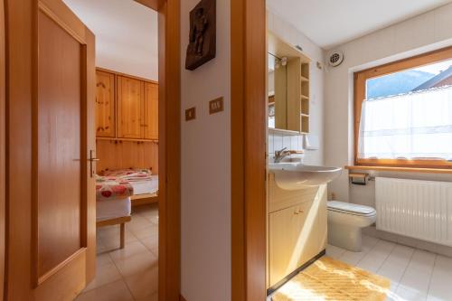baño con lavabo y aseo y ventana en Casa Parente en Pozza di Fassa