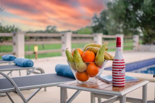 a bowl of fruit on a table next to a bottle at YourHouse Can Cuixa Villa in Can Picafort